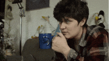 a person is drinking from a blue mug that says " daddy "