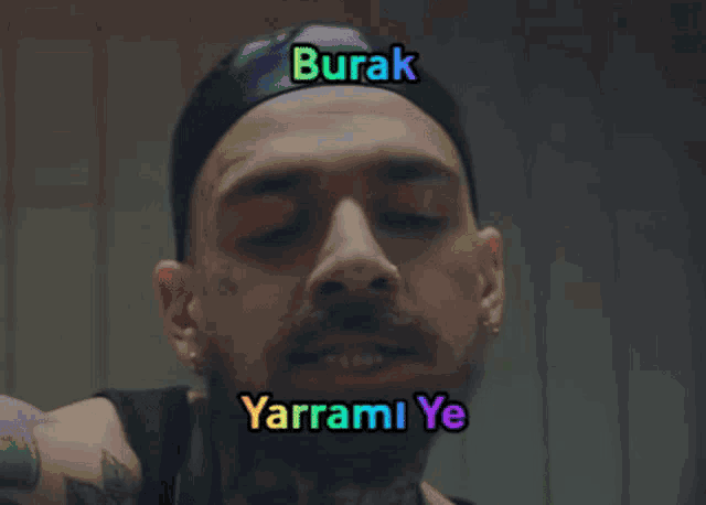 a man with a beard is wearing a black hat and has the words burak yarrami ye written on his face