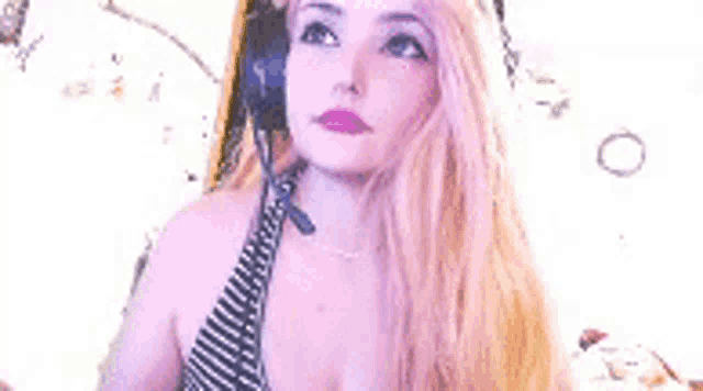 a woman with long blonde hair is wearing headphones and a striped bikini top .