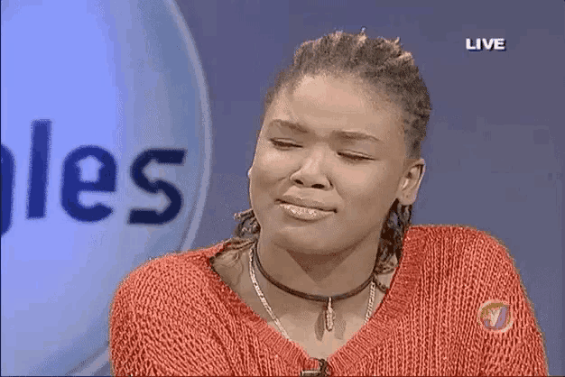 a woman wearing a red sweater is crying in front of a live sign