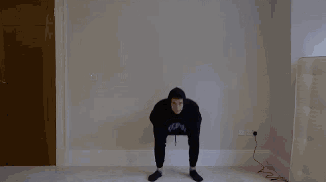 a man in a black hoodie and socks is doing a trick on the floor .