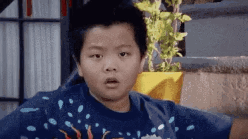 a young boy is making a funny face while wearing a blue sweater .