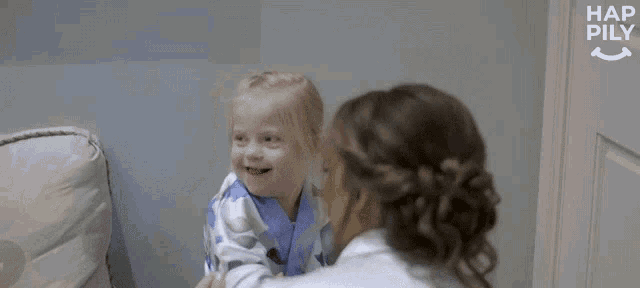 a woman is holding a little girl in her arms and they are looking at each other .