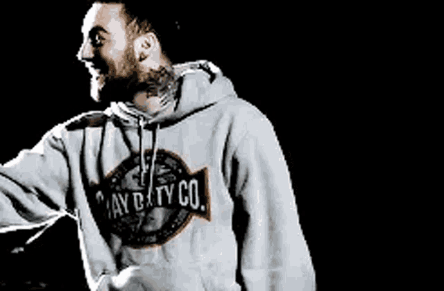 a man in a hoodie is dancing on a stage in the dark .