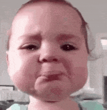 a baby is crying and making a sad face .