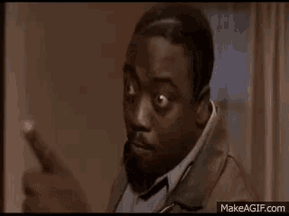 a man in a jacket is standing in a room with his arms outstretched and making a funny face .