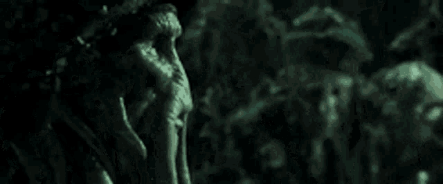 a group of people standing next to each other in a dark room in a movie .