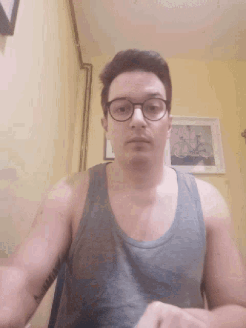 a man wearing glasses and a tank top is looking at the camera