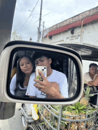 a rear view mirror shows a man taking a picture of a woman