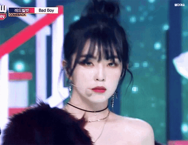 a woman is wearing a choker and earrings while standing on a stage .