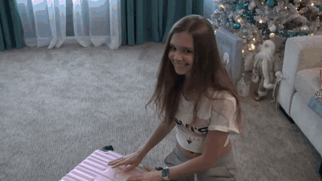 a girl wearing a crop top that says king sits on a pink suitcase