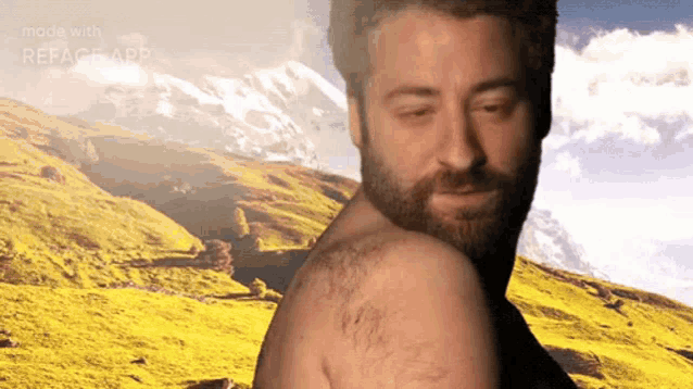 a shirtless man with a beard is standing in front of a mountain range with the words made with reface app below him