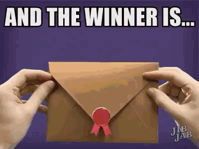 a person is holding a brown envelope with a red ribbon and the words `` and the winner is '' written on it .