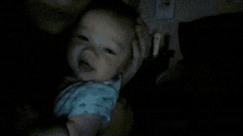 a baby is being held in a dark room by a person