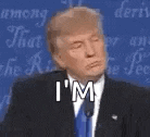 donald trump is wearing a suit and tie and making a funny face while speaking into a microphone .