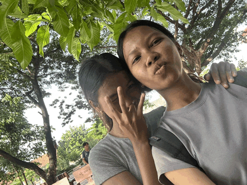 two girls are posing for a picture with one wearing a gray shirt that says asics