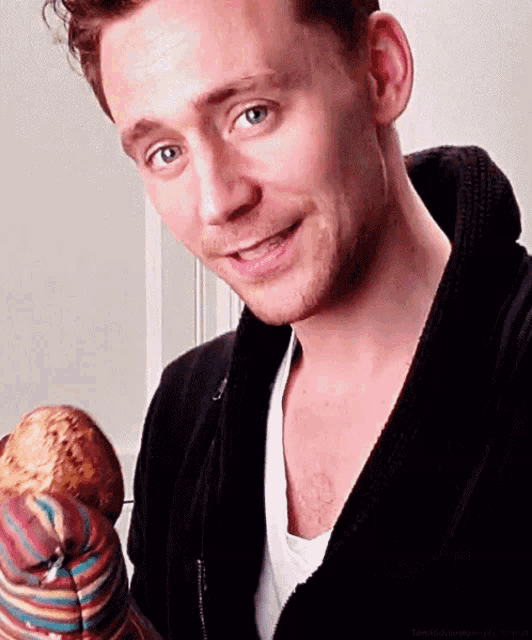 a man in a black robe is holding a stuffed animal in his hands .