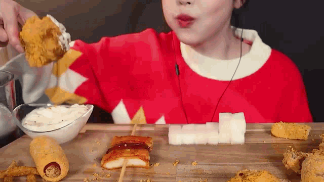 a woman in a red and white sweater is eating fried food