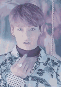 a young man with purple hair is giving the middle finger while wearing a floral shirt and a turtleneck .