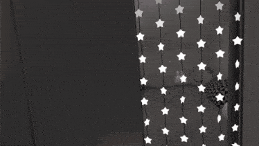 a girl with red eyes is standing in front of a wall with stars on it