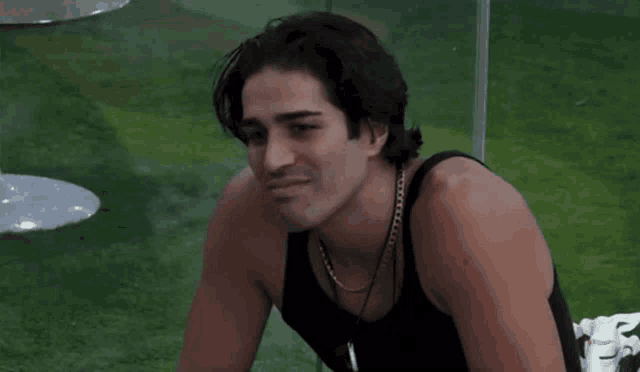 a man wearing a black tank top and a gold chain