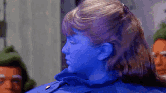a woman with blue paint on her face is standing in front of a group of people .