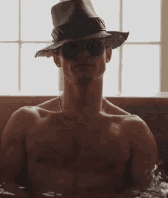 a shirtless man wearing a cowboy hat and sunglasses