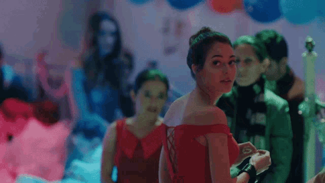 a woman in a red dress is standing in a room with other people