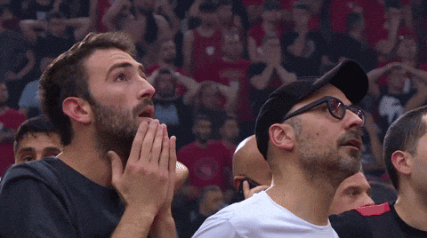 a group of men are watching a basketball game and one of them has glasses on