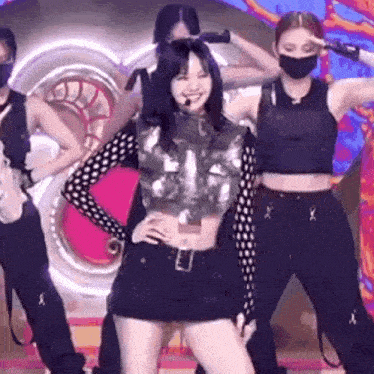 a woman in a crop top and shorts is dancing on a stage with other dancers .