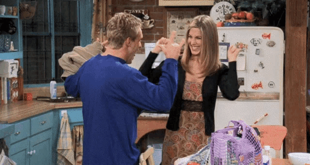 a man and a woman are dancing in front of a refrigerator that has a sign that says coffee shop on it