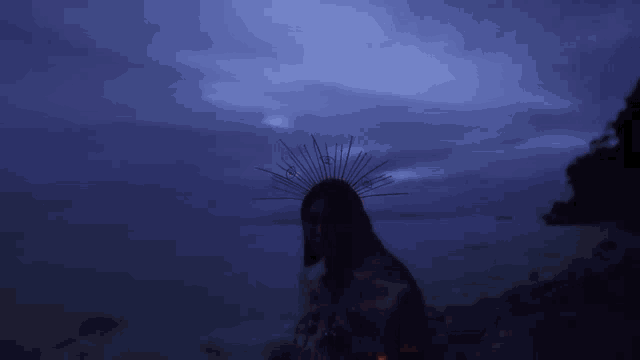 a woman with a crown on her head is standing on a beach at night