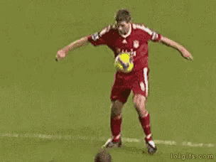 a man in a blue shirt is kicking a soccer ball on a field