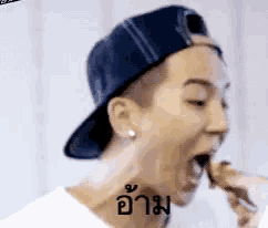 a man wearing a baseball cap and a white shirt is eating something .