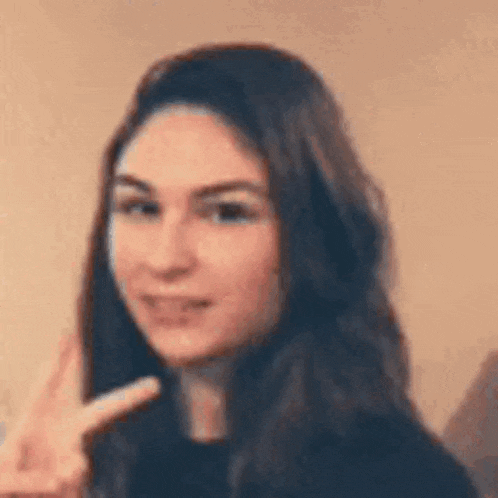 a close up of a woman giving a peace sign .