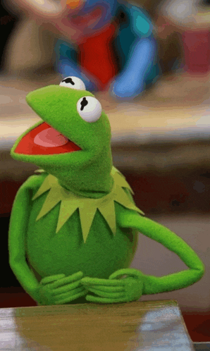 kermit the frog is sitting on a table with his mouth wide open