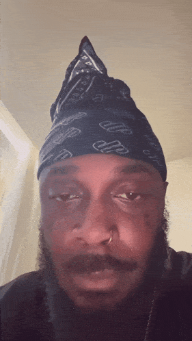 a man with a bandana on his head has a tattoo on his forehead that says ' i 'm sorry '
