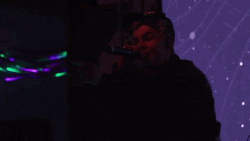 a man singing into a microphone with a hat on that says nasa