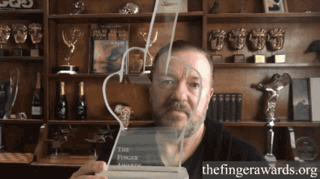 a man is holding a trophy that says the finger awards on it