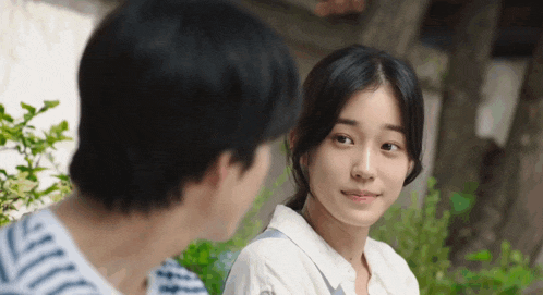 a man and a woman are looking at each other and the girl is smiling