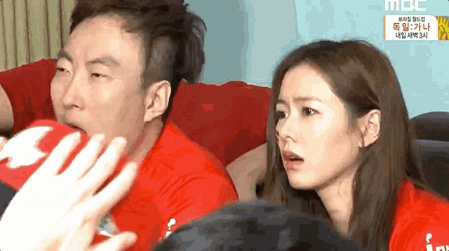 a man and a woman are sitting next to each other and the man is wearing a red shirt that says mbc