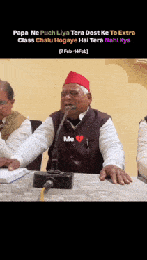 a man in a red hat is sitting at a table with a microphone ..