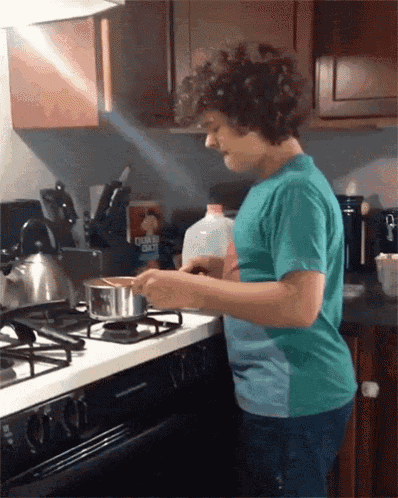 a young boy is cooking in a kitchen with a bottle of quaker oats on the counter