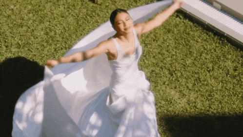 a woman in a white dress is dancing on the grass
