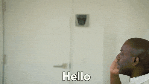 a man and a woman are standing in a doorway and the woman is waving and the man is saying " hello "