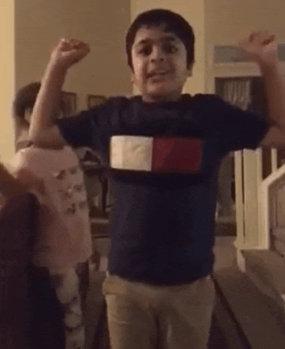 a young boy in a tommy hilfiger shirt is flexing his muscles .
