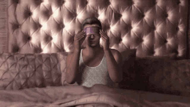 a man wearing a purple blindfold is laying in bed