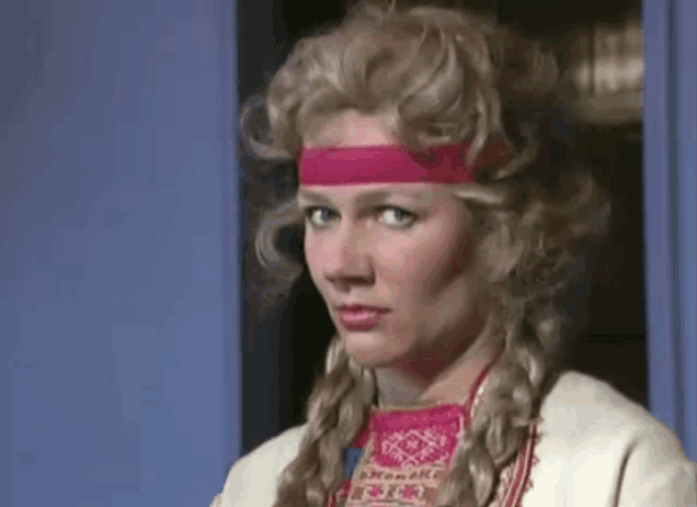a woman wearing a wig and a headband is standing in front of a door .