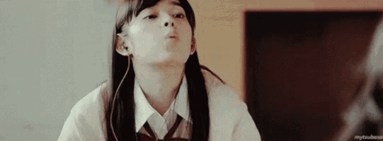 a girl in a school uniform is wearing headphones and making a face .