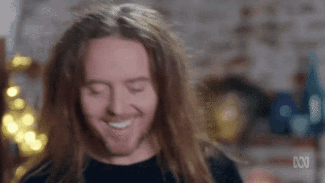 a man with very long hair is smiling with his eyes closed